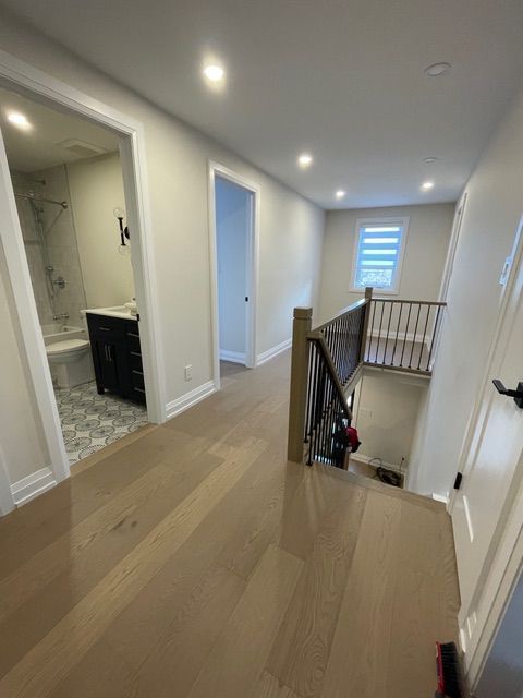 Hallway with wood floors, doors, and a staircase leading down to a lower level.