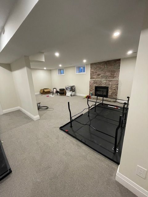 Spacious finished basement with fireplace, gray carpet, and a large black table on the right.