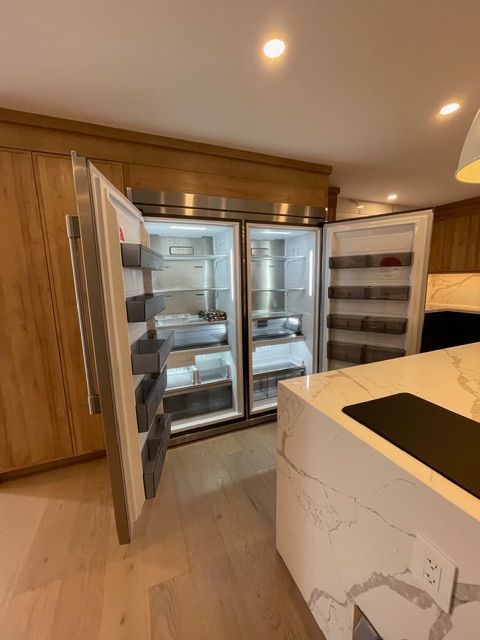Open stainless steel refrigerator in a modern kitchen with a marble countertop.