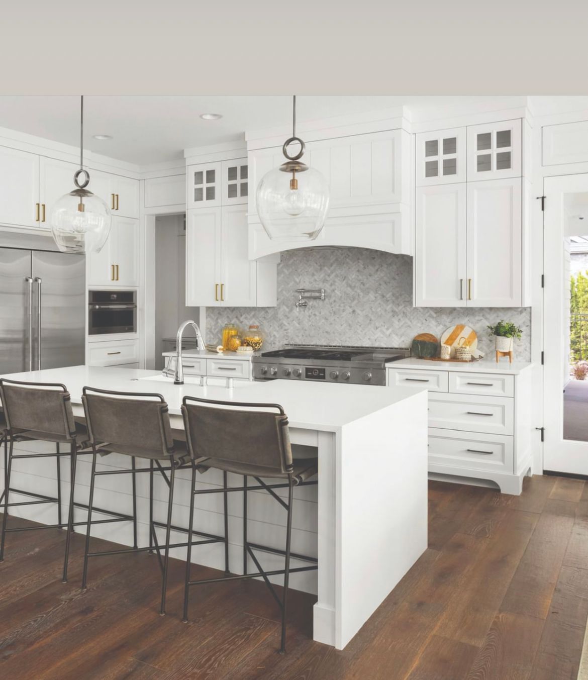 A kitchen with white cabinets , stainless steel appliances , and a large island.