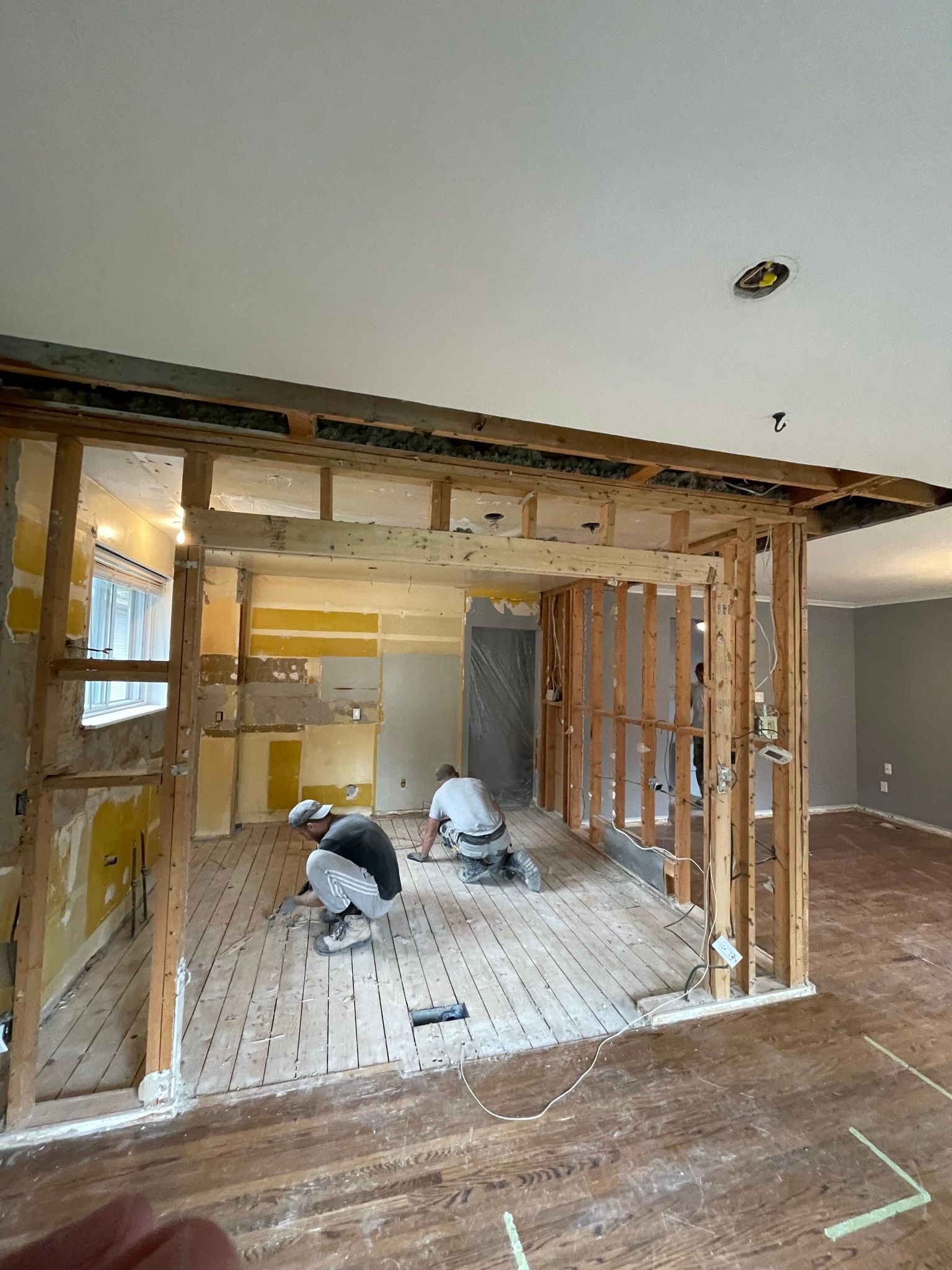 A couple of men are kneeling on the floor in a living room.