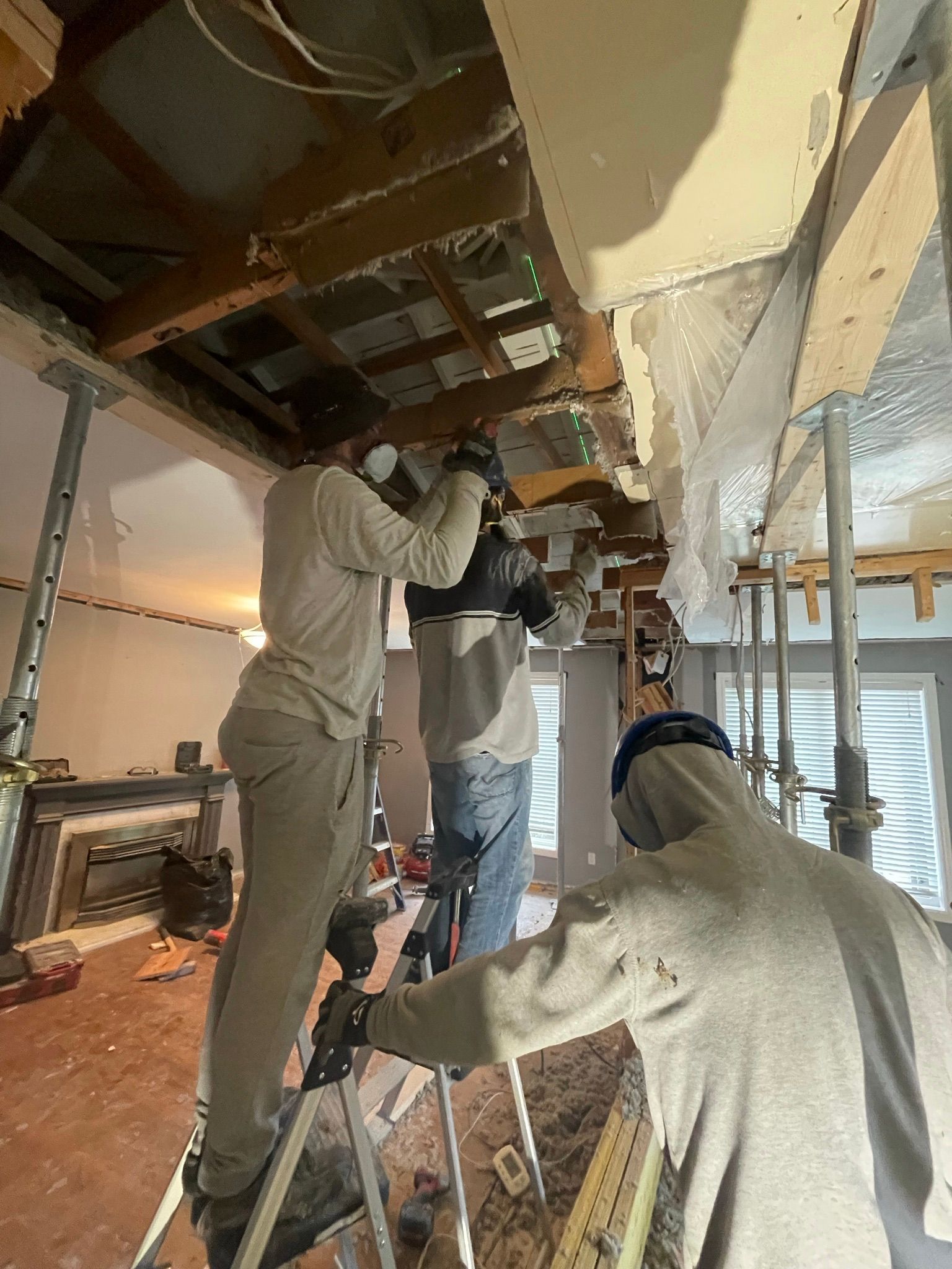 A group of men are working on a ceiling in a room.