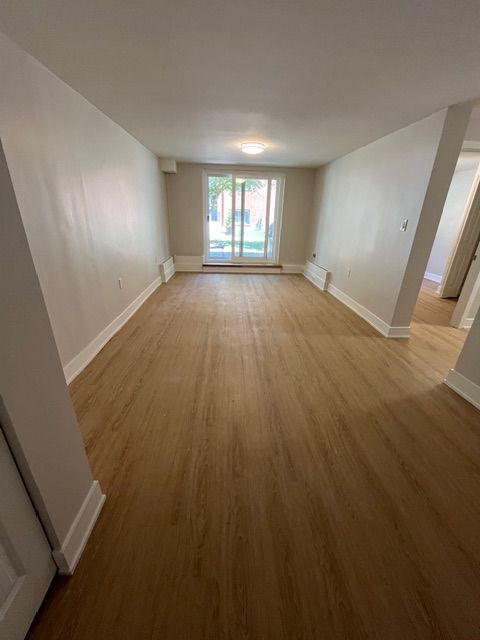 Empty room with wood floors and sliding glass door. White walls and trim.
