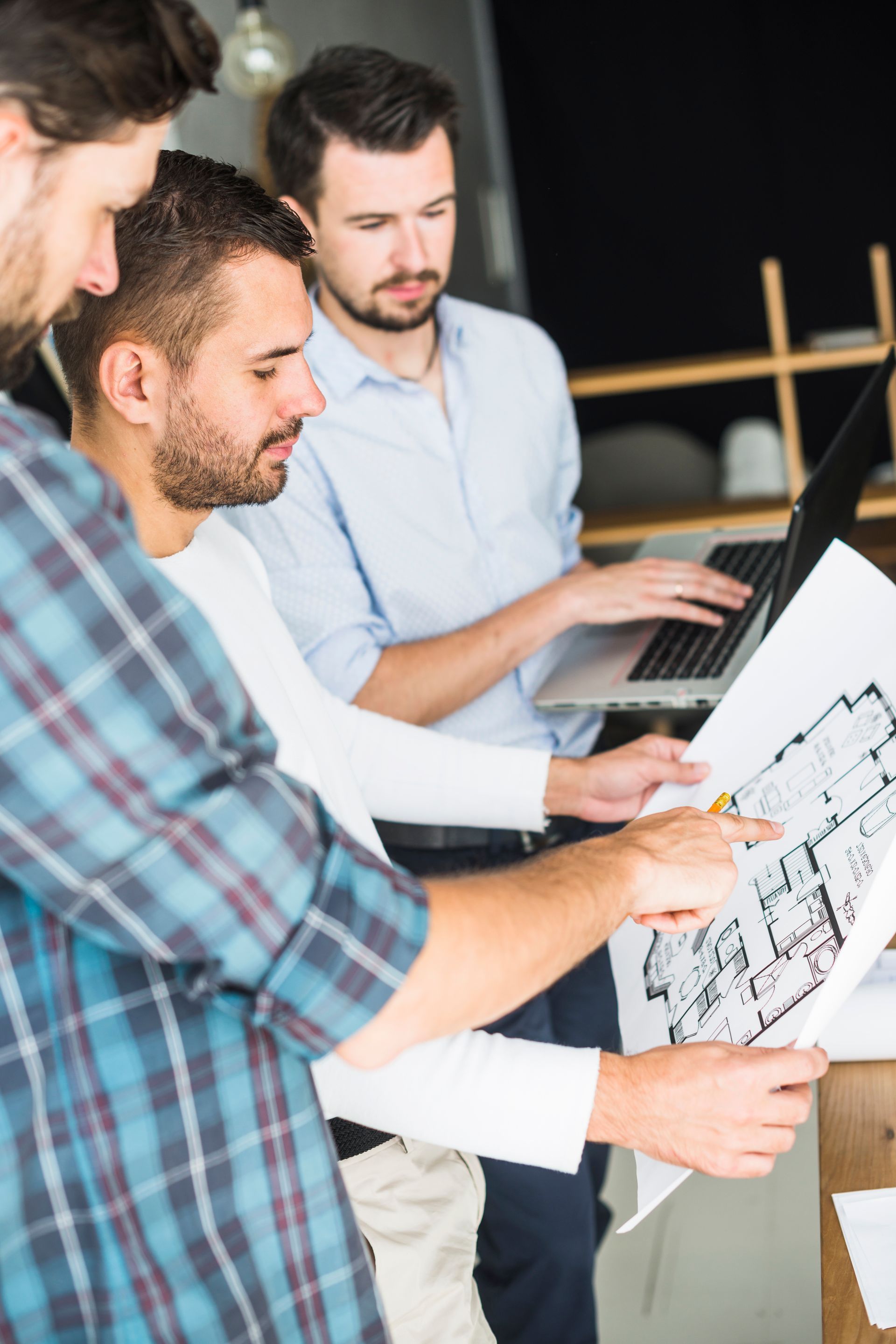 A group of men are looking at a blueprint of a house.