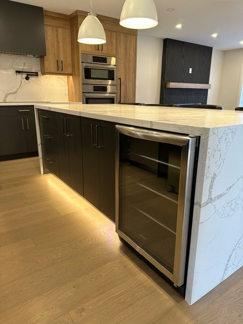 A kitchen with a large island and a wine cooler