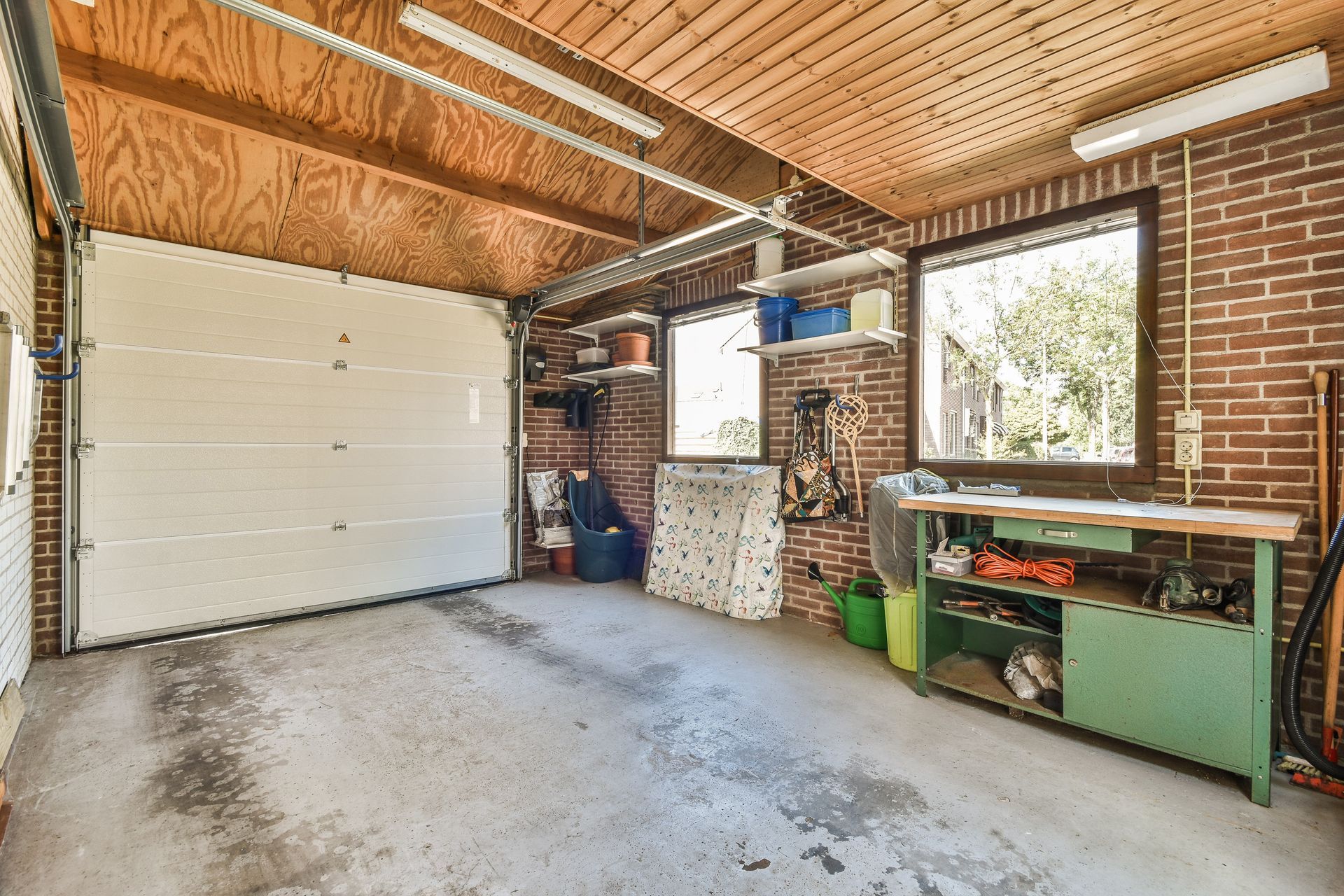 An empty garage with a garage door and a workbench.