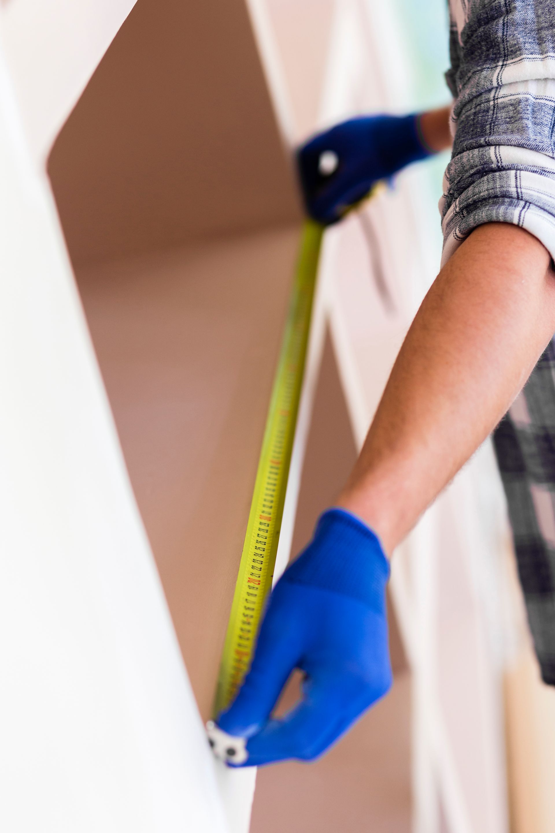 A person is measuring a wall with a tape measure.