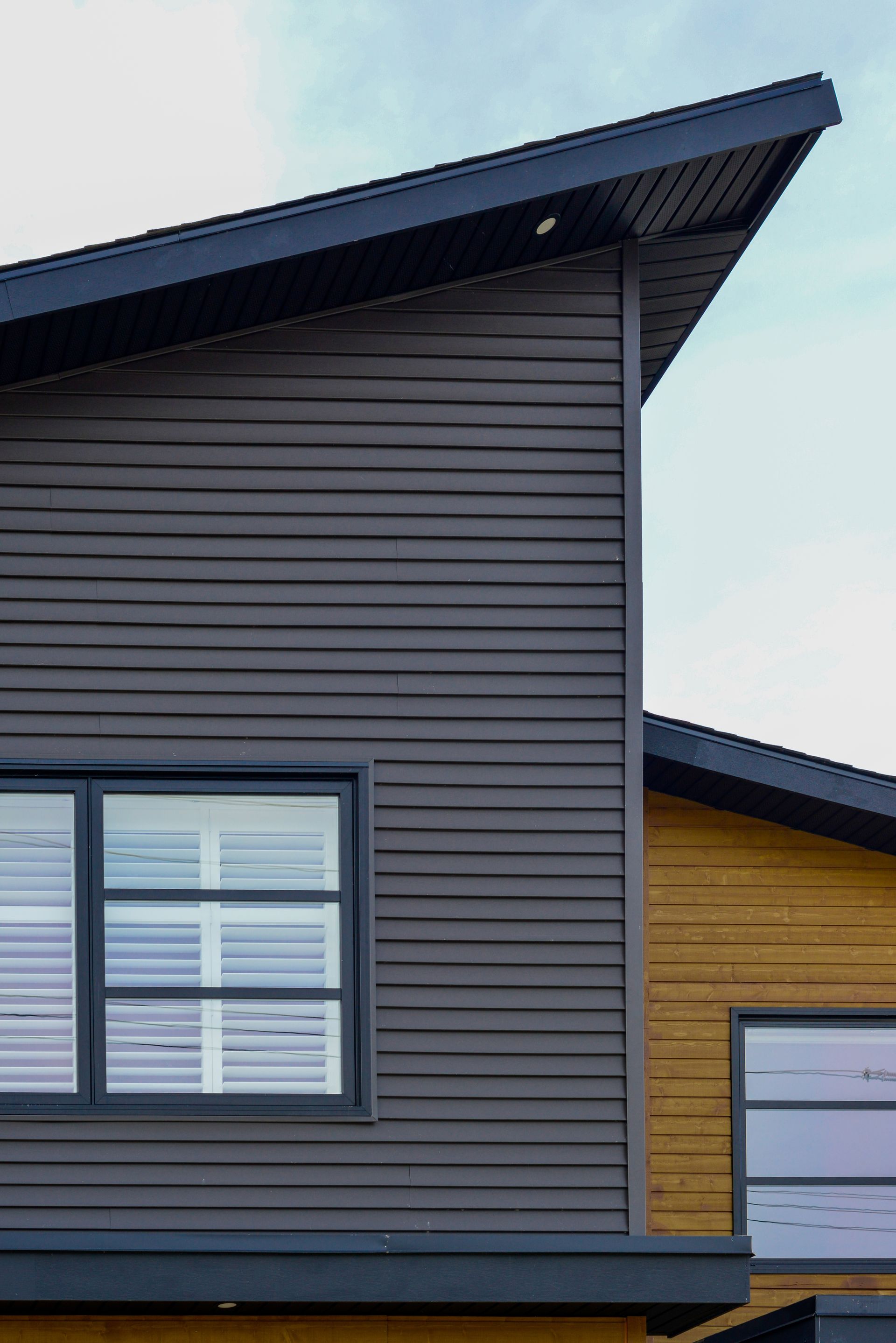 A close up of a house with a black roof and a window.