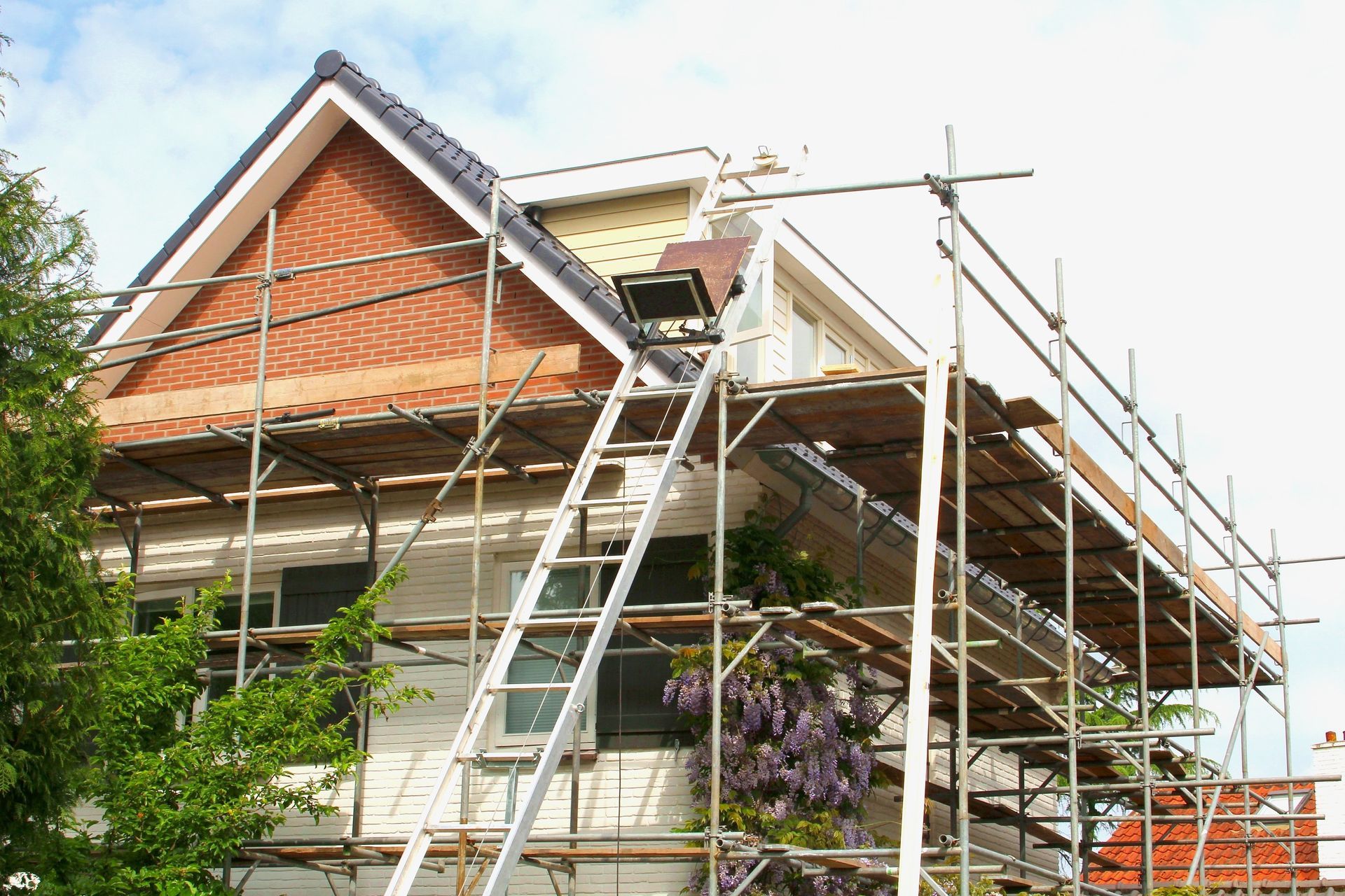 A house is being built with scaffolding and a ladder.