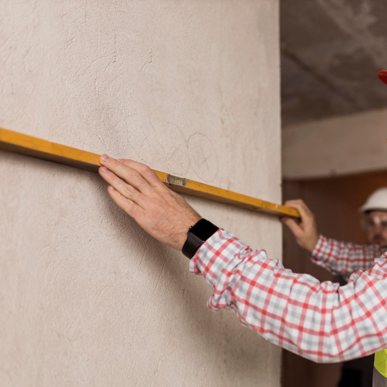 A man is measuring a wall with a level.