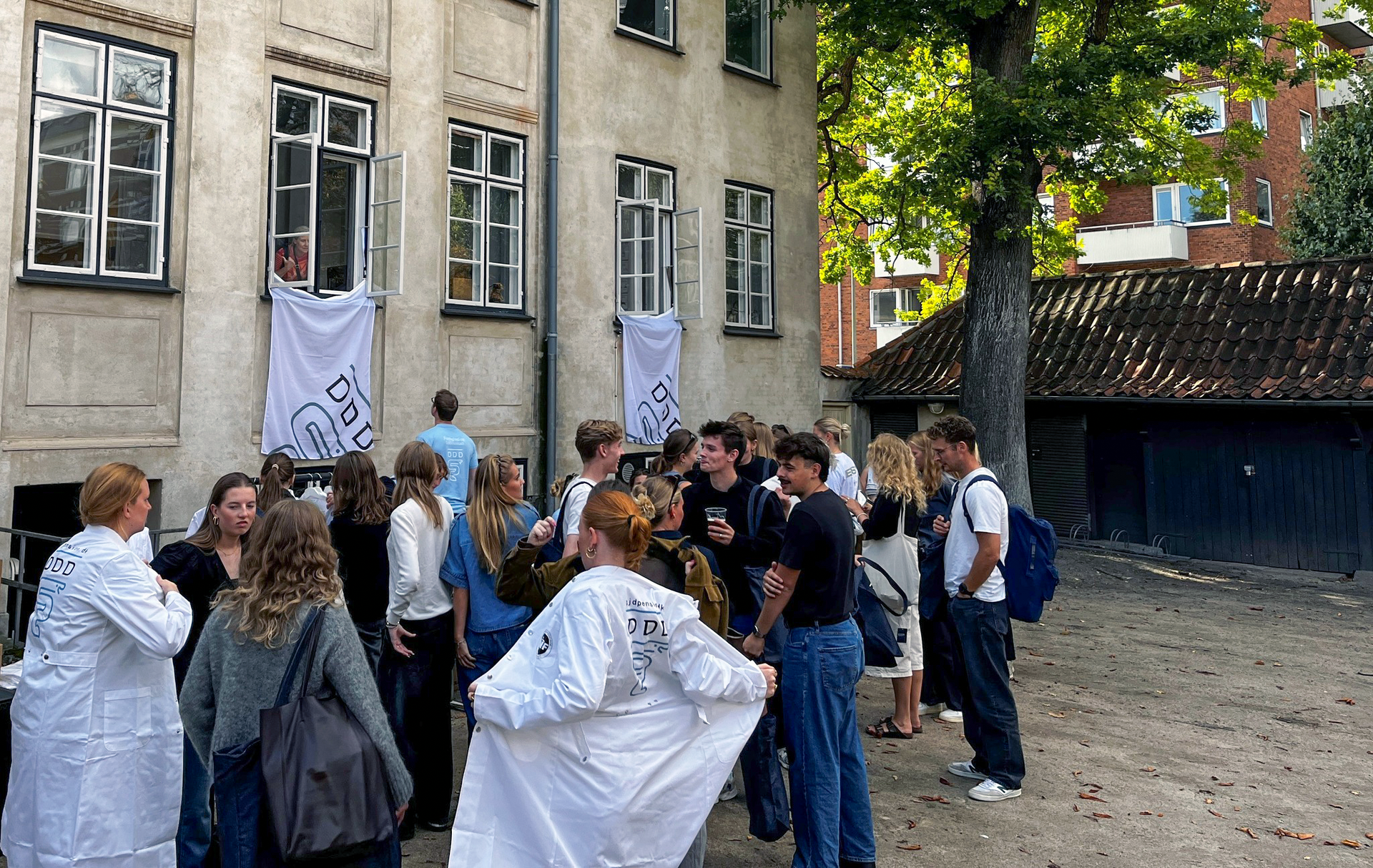 Group of students outside a building with banners hanging from windows.