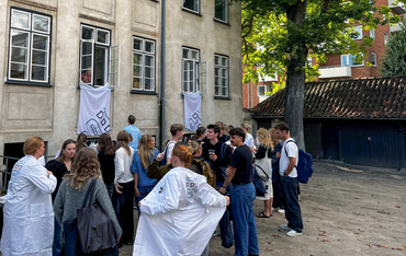 Group of students outside a building with banners hanging from windows.