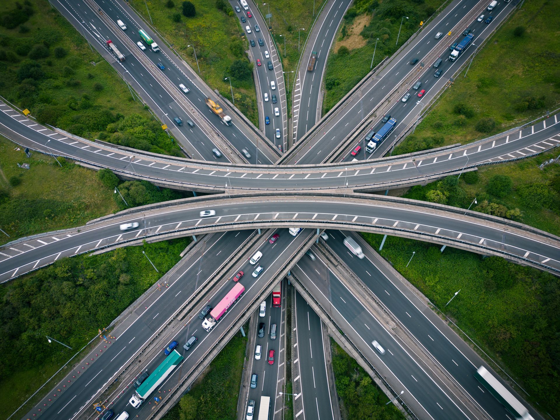 Aerial view of a multi-level highway interchange with numerous vehicles traveling between the roads.