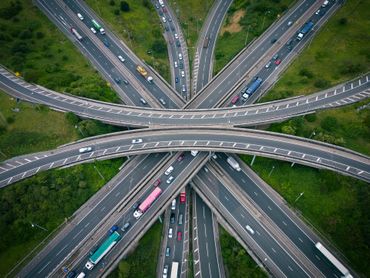 Aerial view of a multi-level highway interchange with numerous vehicles traveling between the roads.