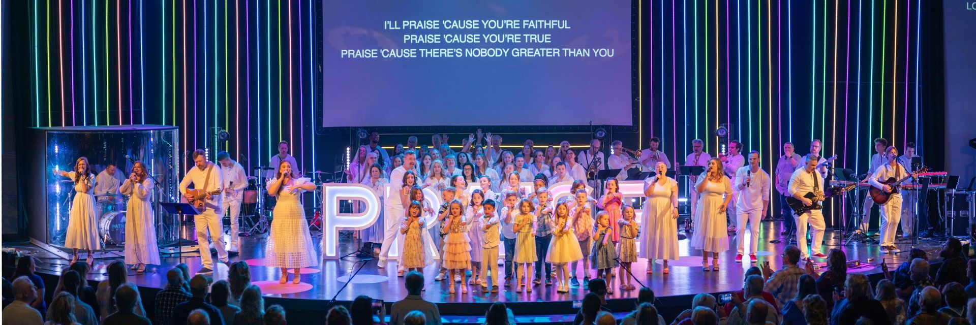 A large group of people are standing on a stage in front of a large screen.