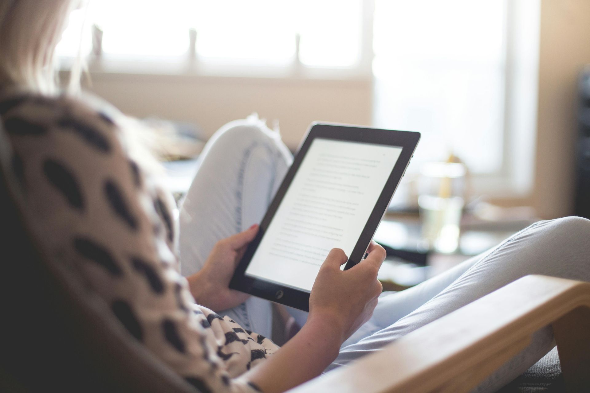 A woman is sitting in a chair using a tablet computer.