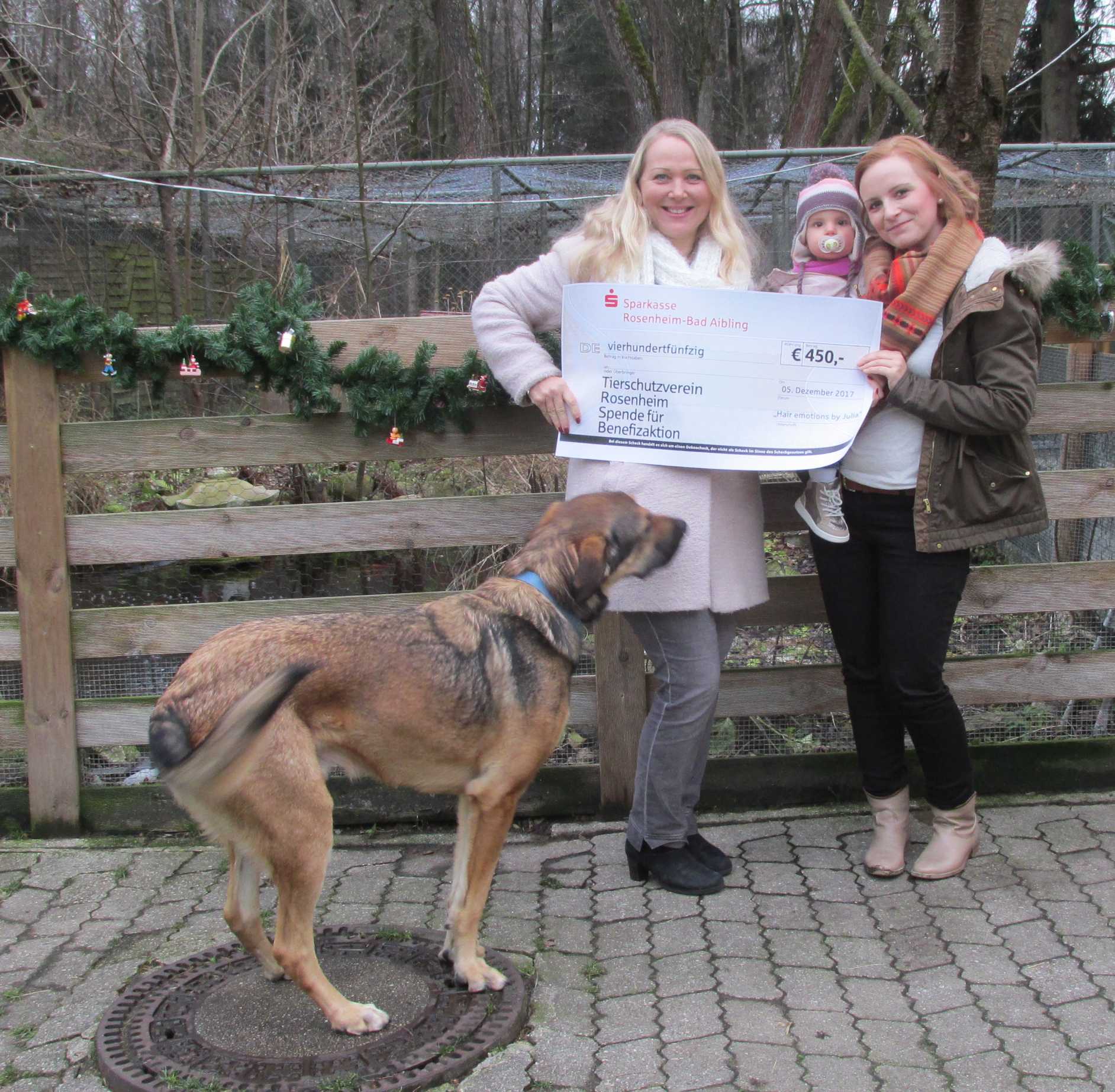 Eine Frau mit einem Scheck steht neben einem Hund