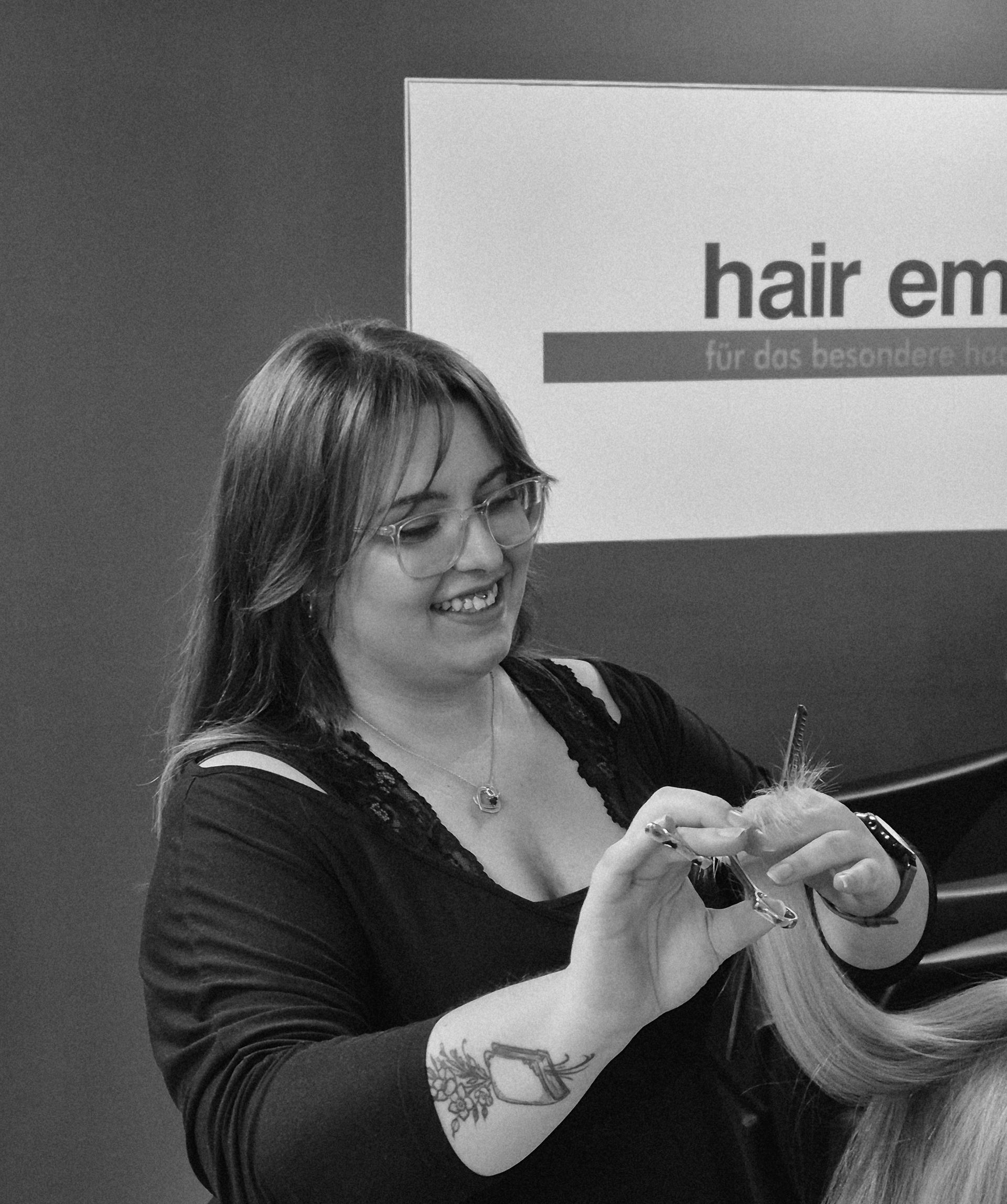 Eine Frau föhnt einer Frau die Haare vor einem Schild mit der Aufschrift „Emo“