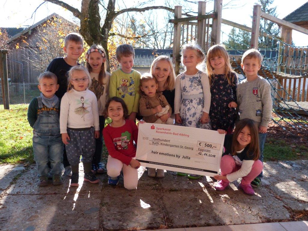 Eine Gruppe Kinder posiert für ein Foto und hält dabei einen Scheck in der Hand.