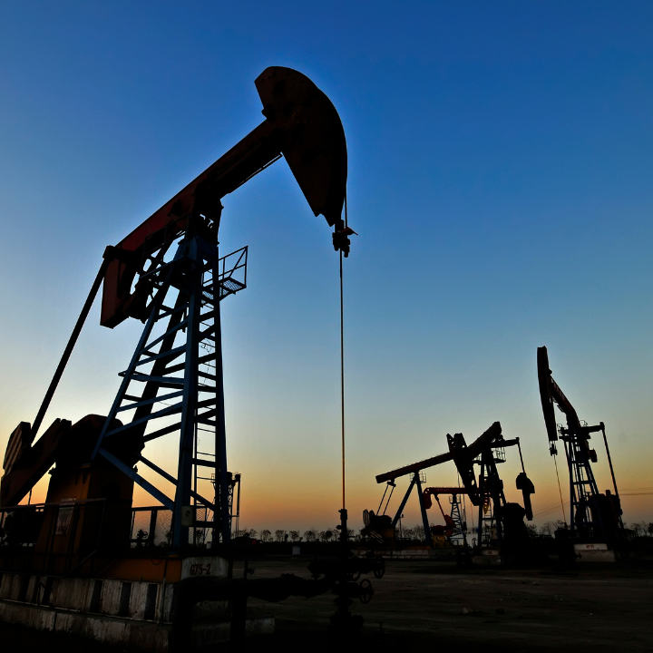 Silhouetted oil pumps against a dusk sky.