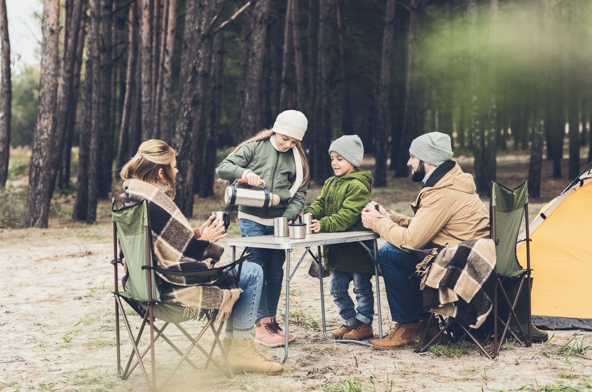 A family is sitting at a table in the woods.