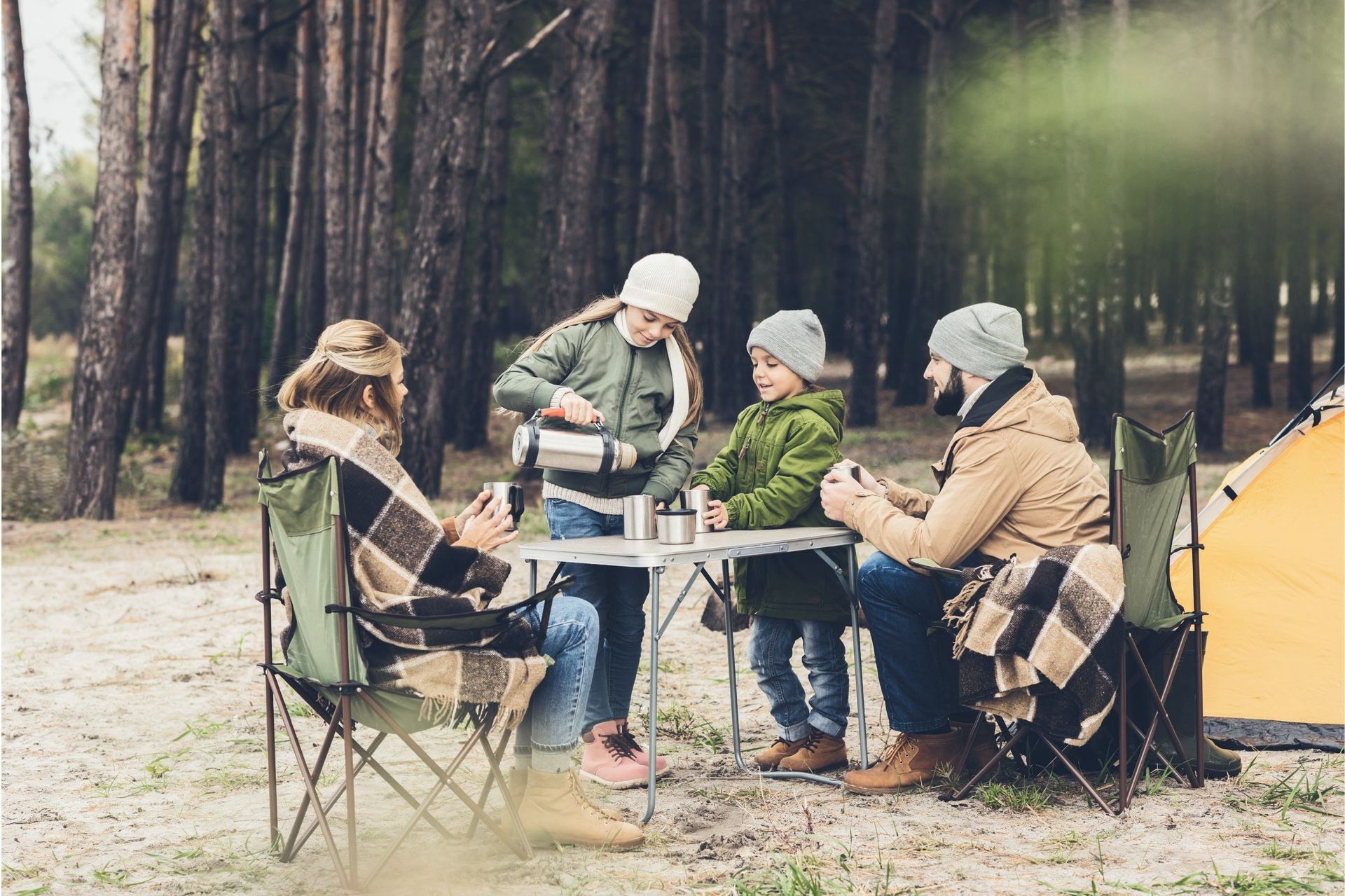 A family is sitting at a table in the woods.