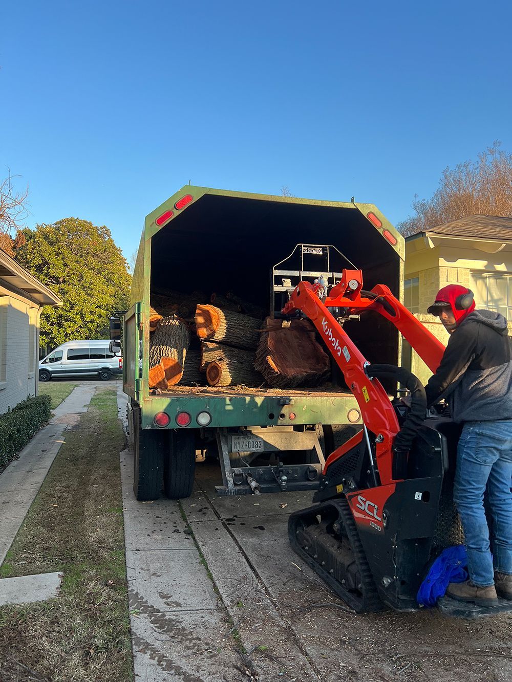 A man is loading logs into a truck with a machine.