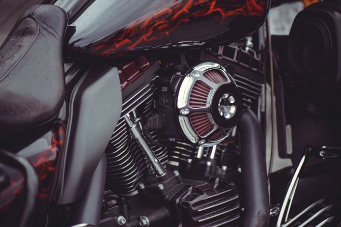 Primo piano del motore di una motocicletta nera e rossa con dettagli cromati e sella in pelle.