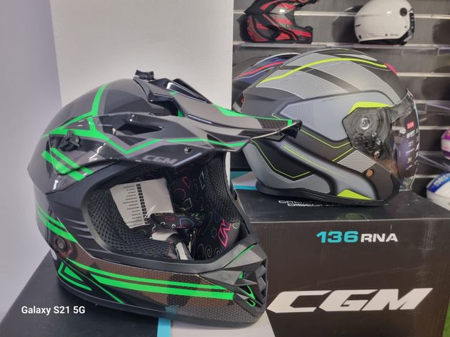 Due caschi da motociclista neri, verdi e grigi esposti in un negozio o in uno showroom.