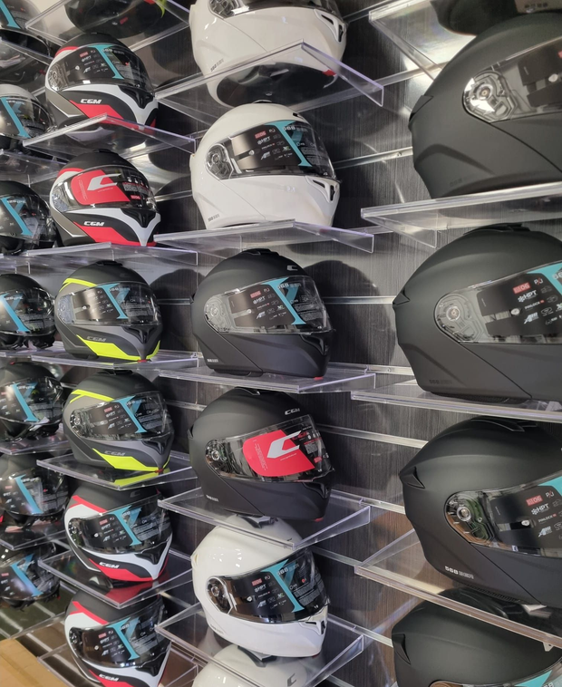 File di caschi da motociclista neri, bianchi, rossi e con dettagli fluo sugli scaffali dei negozi.