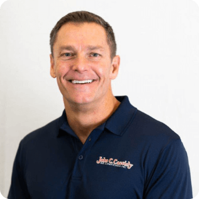 Smiling man in navy polo shirt; text on shirt reads 