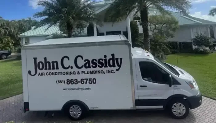 White John C. Cassidy Air Conditioning & Plumbing service van parked in front of a house.