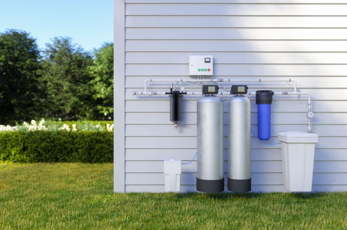 Whole house water filtration system installed outdoors to purify residential tap water.
