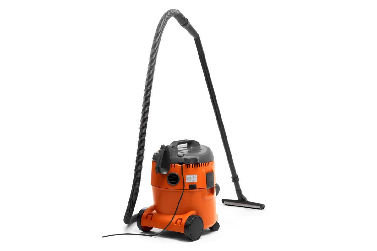 Orange wet/dry vacuum with black hose and floor attachment on a white background.
