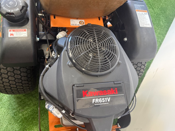 Close-up of a Kawasaki FR651V engine on a riding mower, with grass in the background