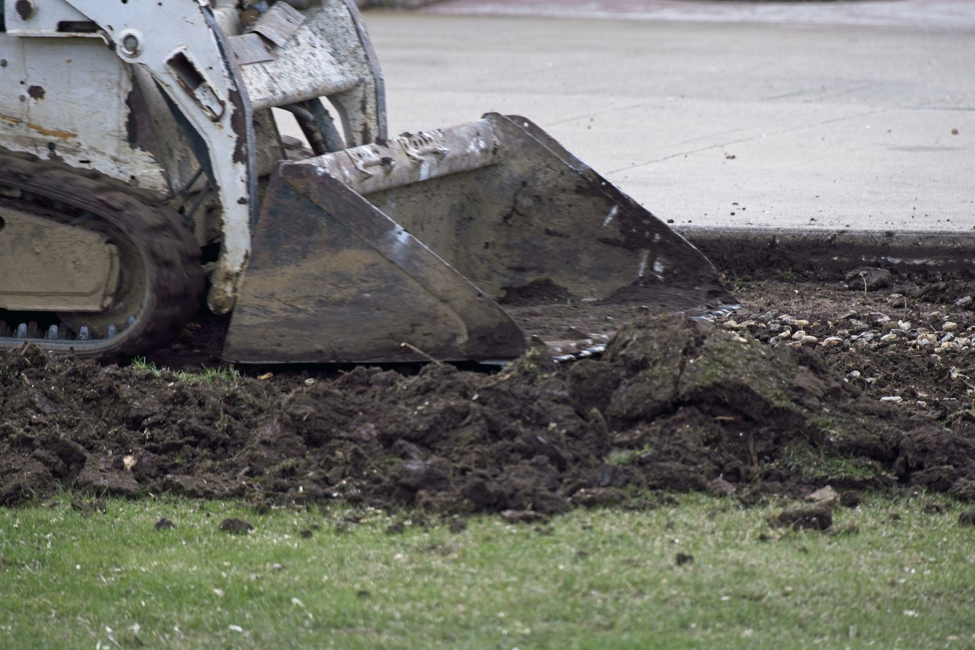 Excavator on a construction site next to a pile of sand under a blue sky.