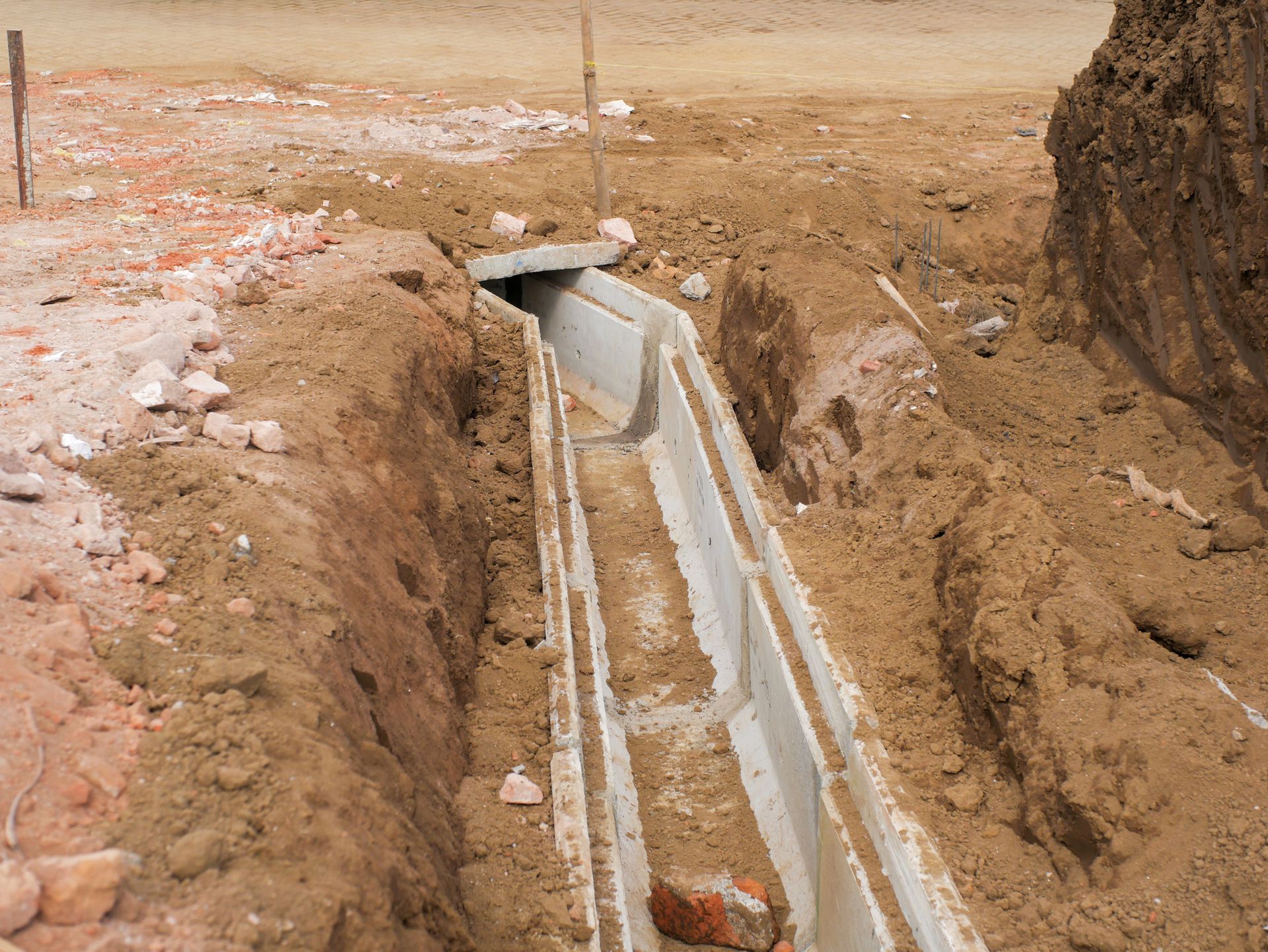Concrete drainage channel under construction in dirt, with debris.