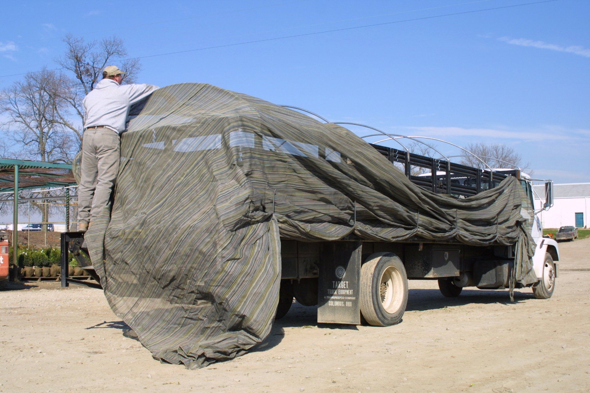 A truck being covered by a shade tarp.