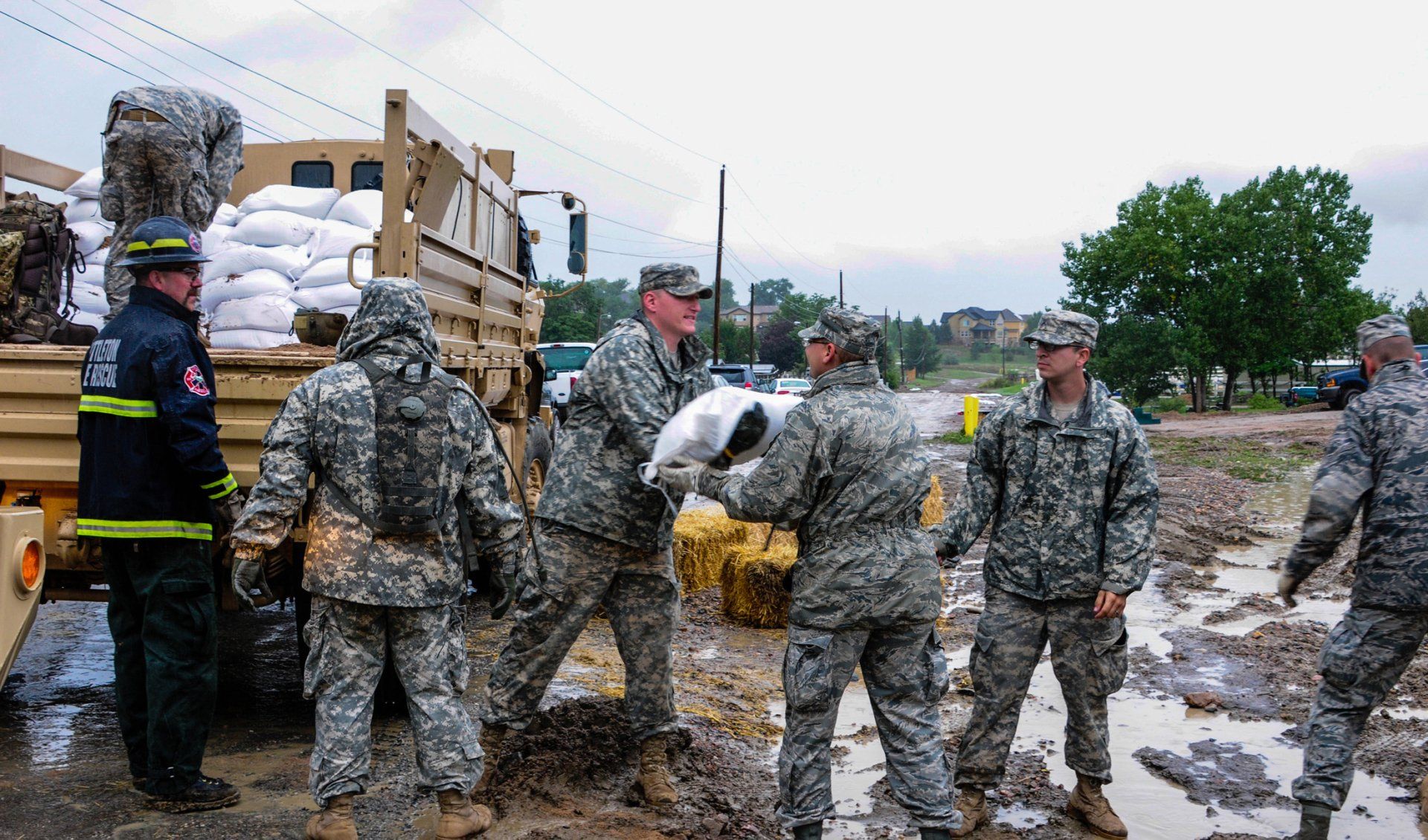 The national guard moving sandbags off a truck.