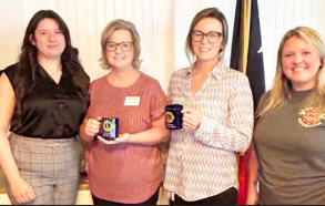 A group of women are standing next to each other holding coffee mugs.