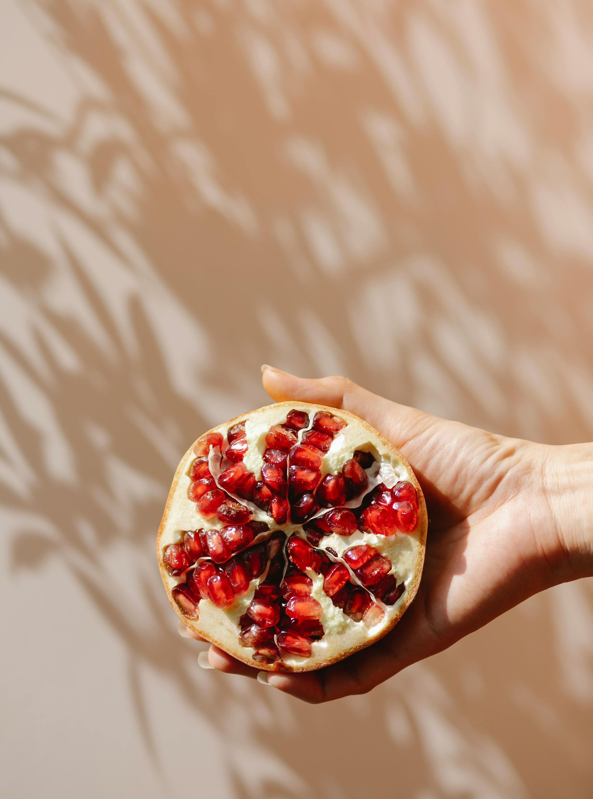 Woman holding half a pomegranate and you can see the fresh inside 