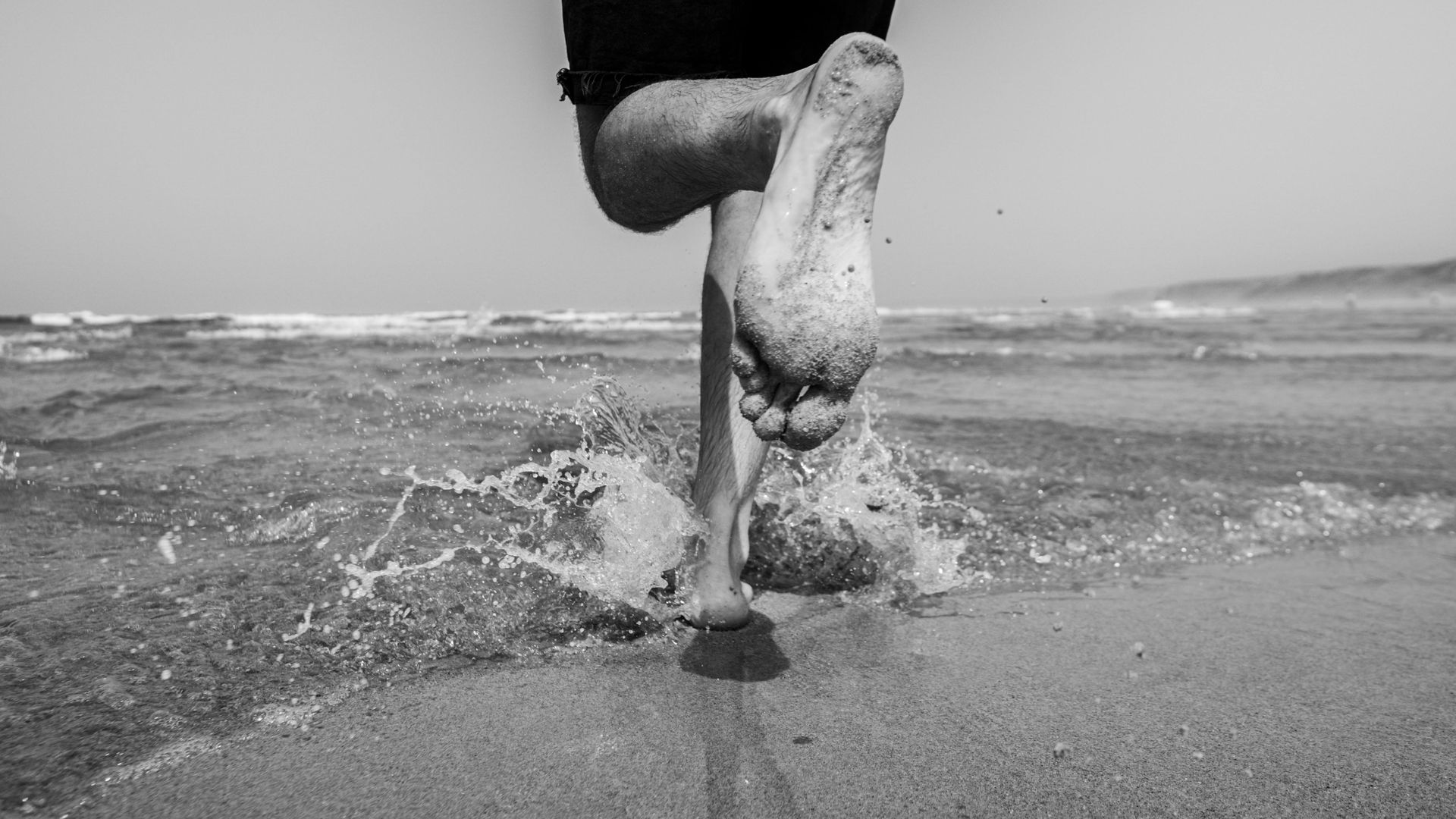 Running on the beach, with feet running through the water