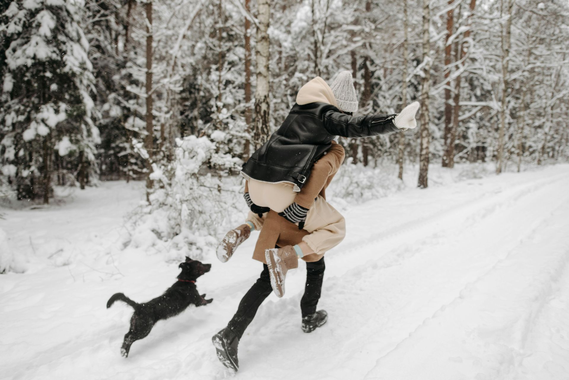 Couple running in the snow with their dog and healthy legs and feet