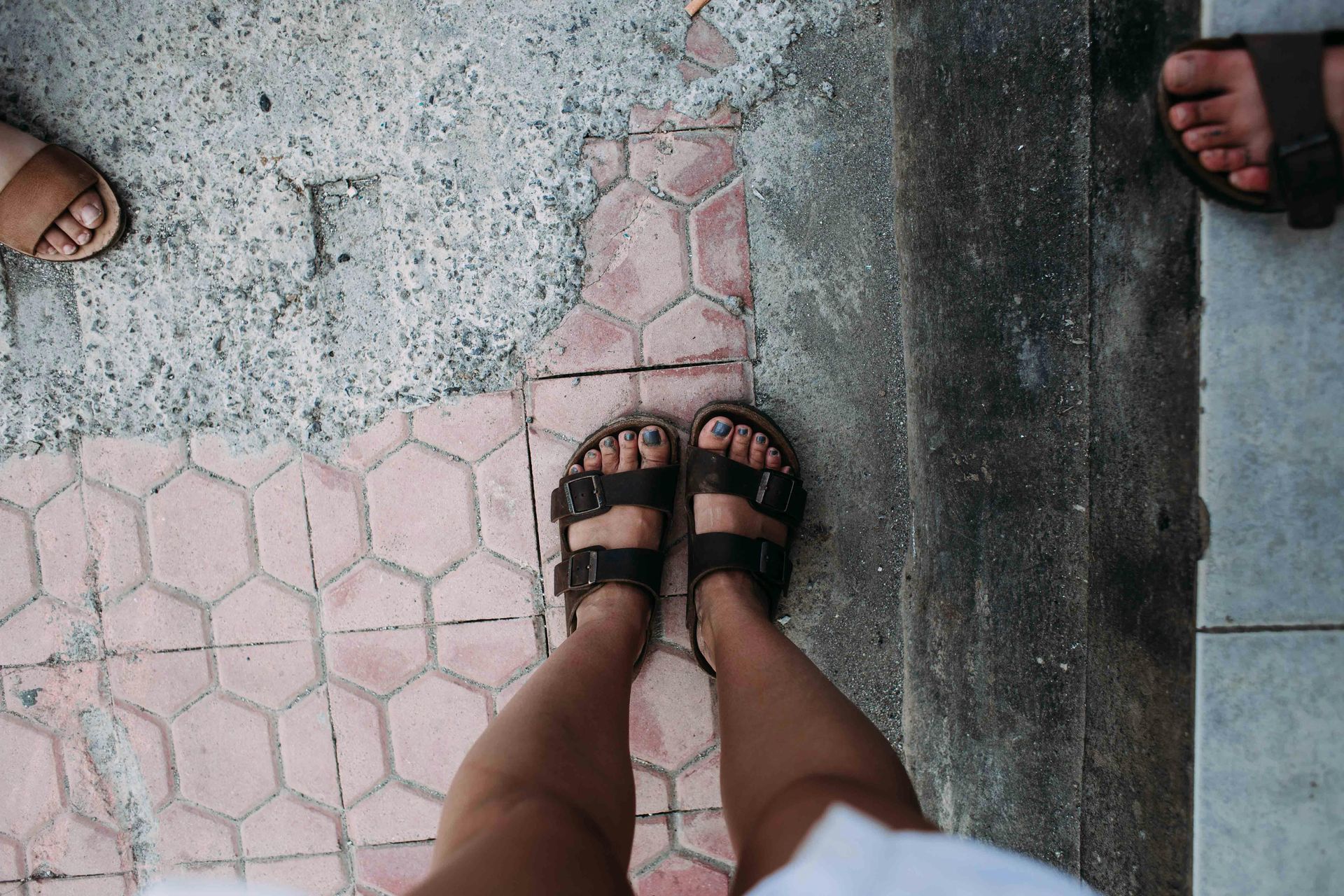 three pairs of feet in summer sandals