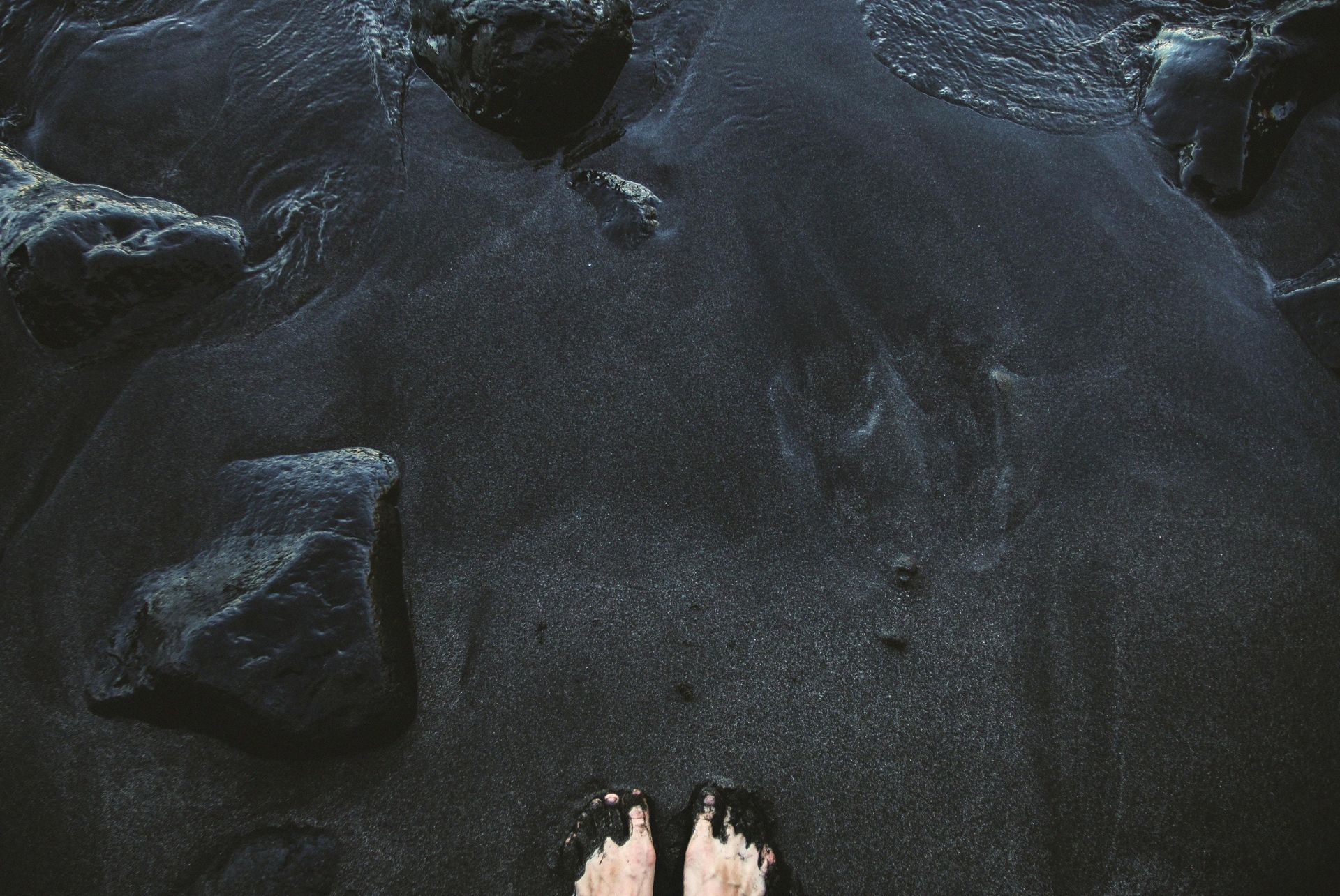 Feet in black sands on an island