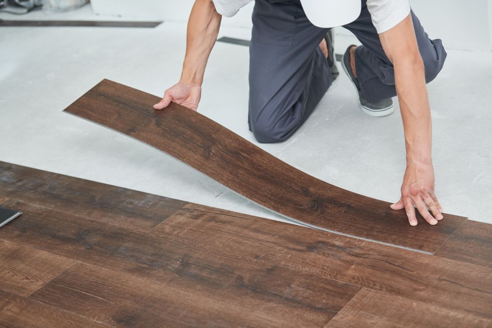 A man is installing a wooden floor in a room.