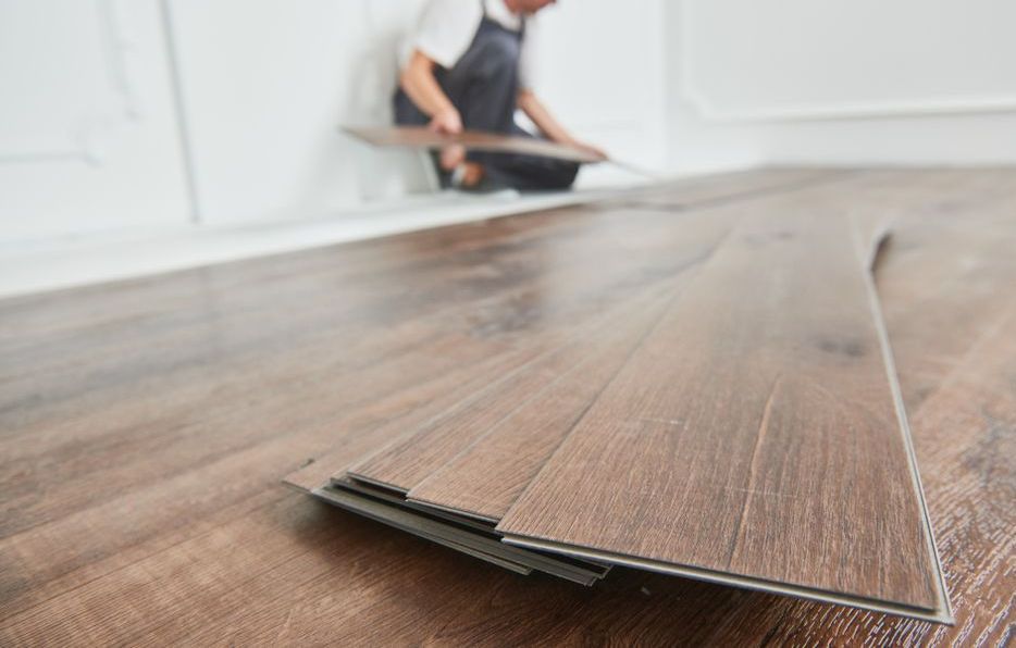 A man is installing a wooden floor in a room.