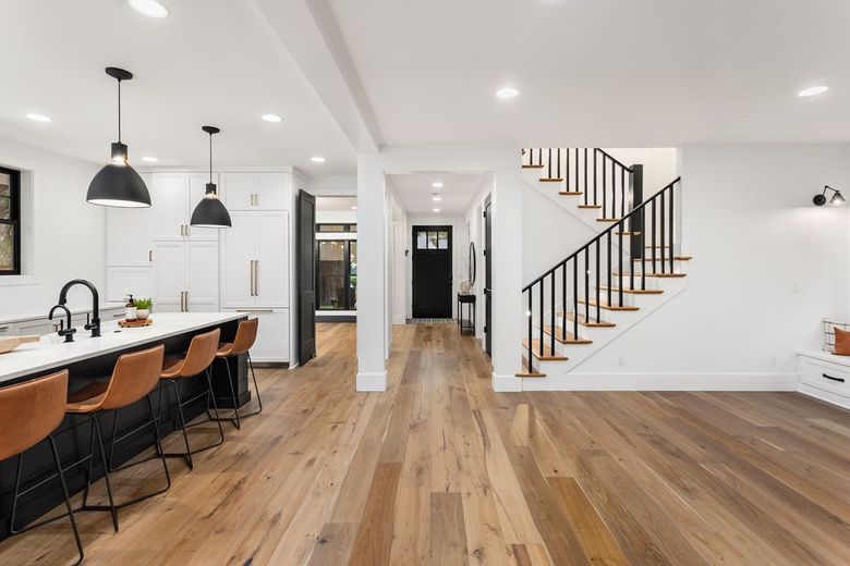 A kitchen with hardwood floors and a staircase leading up to the second floor.