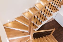 An aerial view of a wooden staircase with a black railing