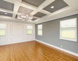 A large empty room with hardwood floors and a chandelier.